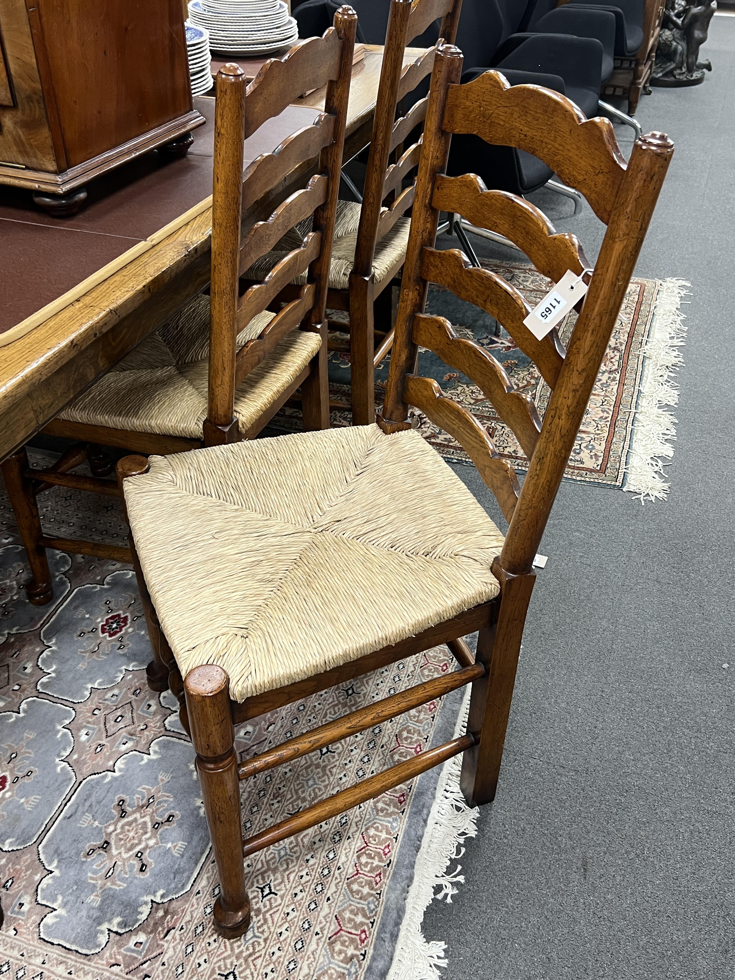 An 18th century style rectangular oak refectory dining table with cleated planked top on square tapered legs, width 213cm, depth 91cm, height 75cm together with a set of six oak rush seat ladderback dining chairs